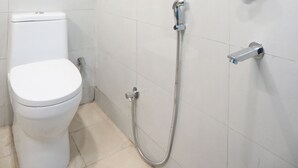 A bathroom with a toilet, a shower, and a water heater. - Hotel Raaso Inn Tuglkabad (New Delhi)