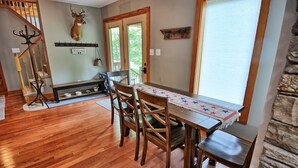 A dining area with a wooden table and chairs, a coat rack, a deer head decoration, and a bench.