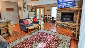 A living room with a fireplace, a television, a dining area, and a kitchen.
