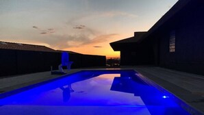 A swimming pool with blue lighting at dusk.