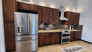 A modern kitchen with dark wooden cabinets, stainless steel appliances, and a granite countertop.