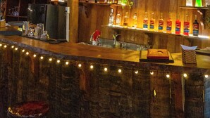 A bar area with a neon sign reading "Sunset Bar," wooden bar counter, hanging lanterns, and a rustic ceiling. - TENT GLAMPING -MUINE SUN & SEA  (Mui Ne)