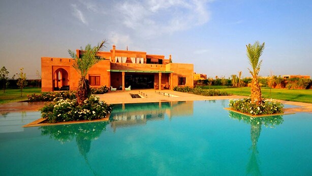 A resort with a large pool, a building with arched windows, and palm trees. - VICTOR HOME RENT (Jbilate)