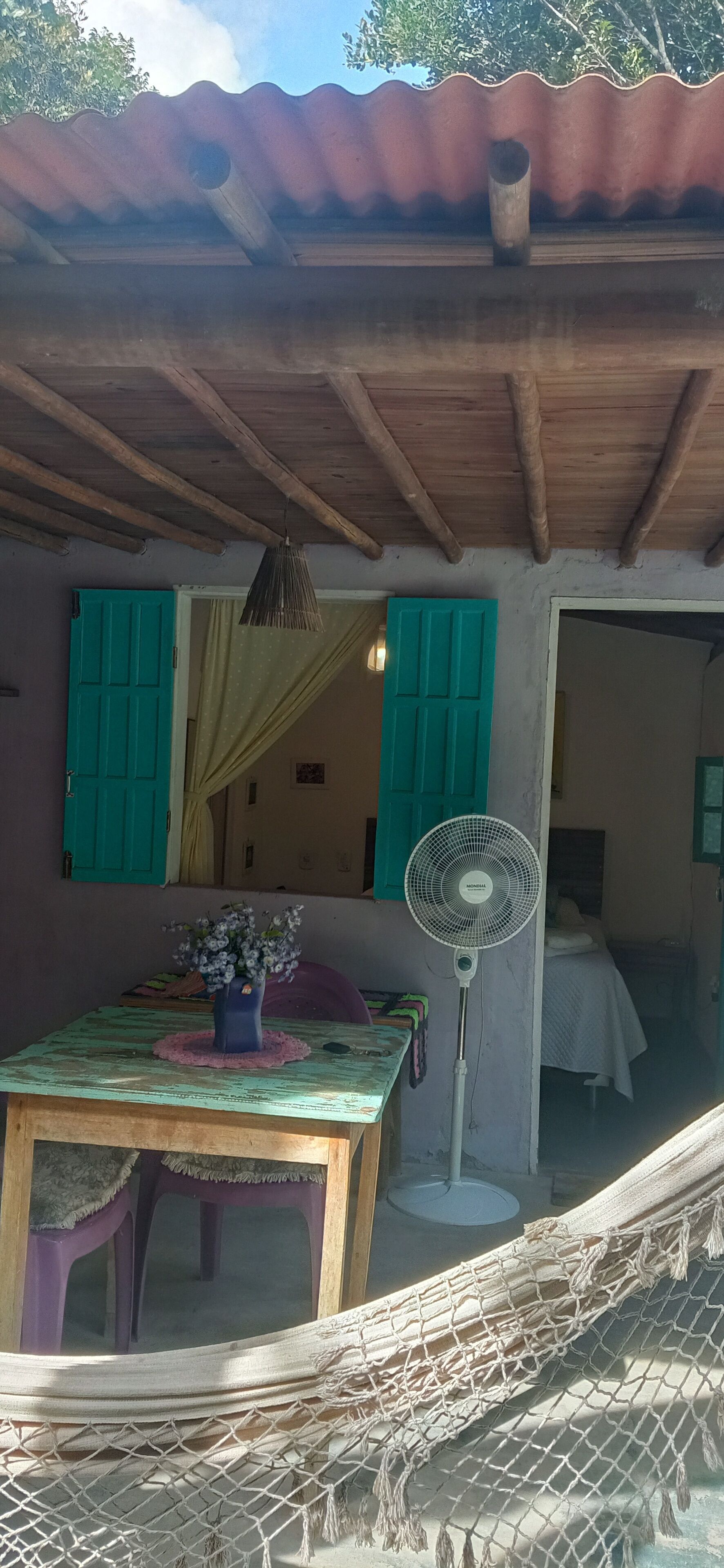 A room with a wooden table, a fan, and a hammock.