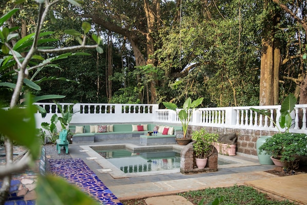 Un jardín tranquilo con piscina, zonas de descanso y plantas en macetas.