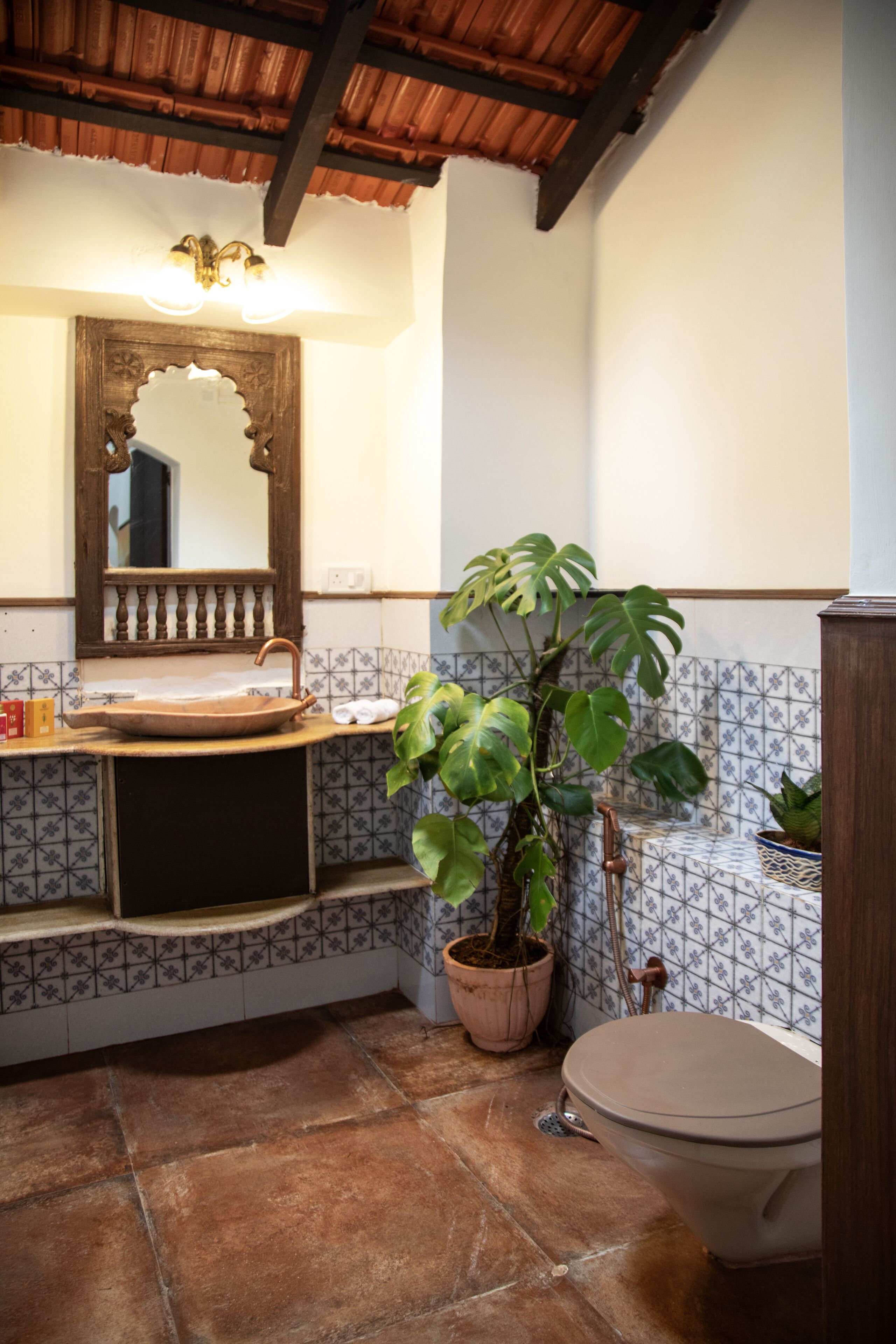 A bathroom with a wooden sink, a large mirror, a potted plant, and a toilet.