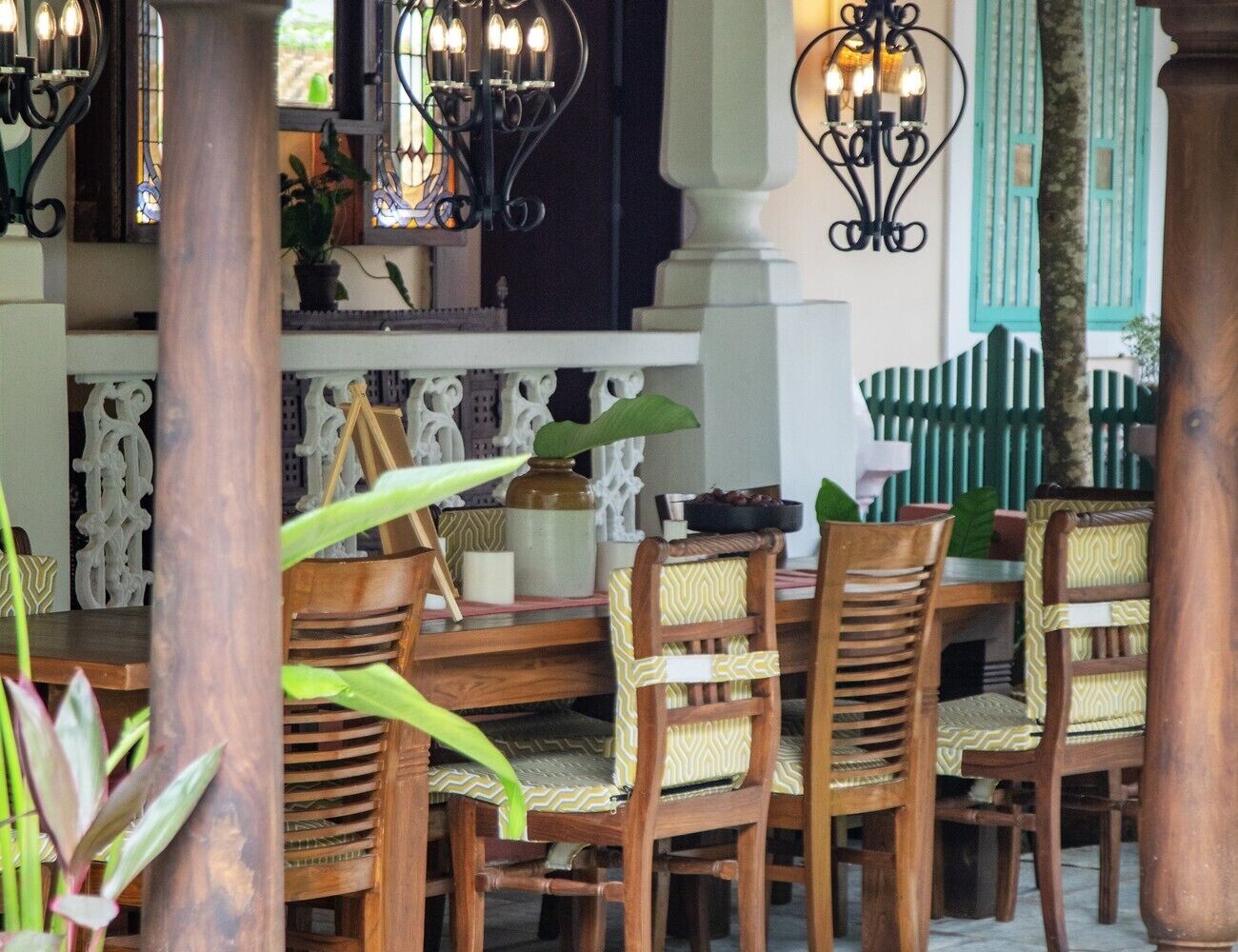 Un espace repas comprenant une table et des chaises en bois, un éclairage décoratif et une balustrade blanche.