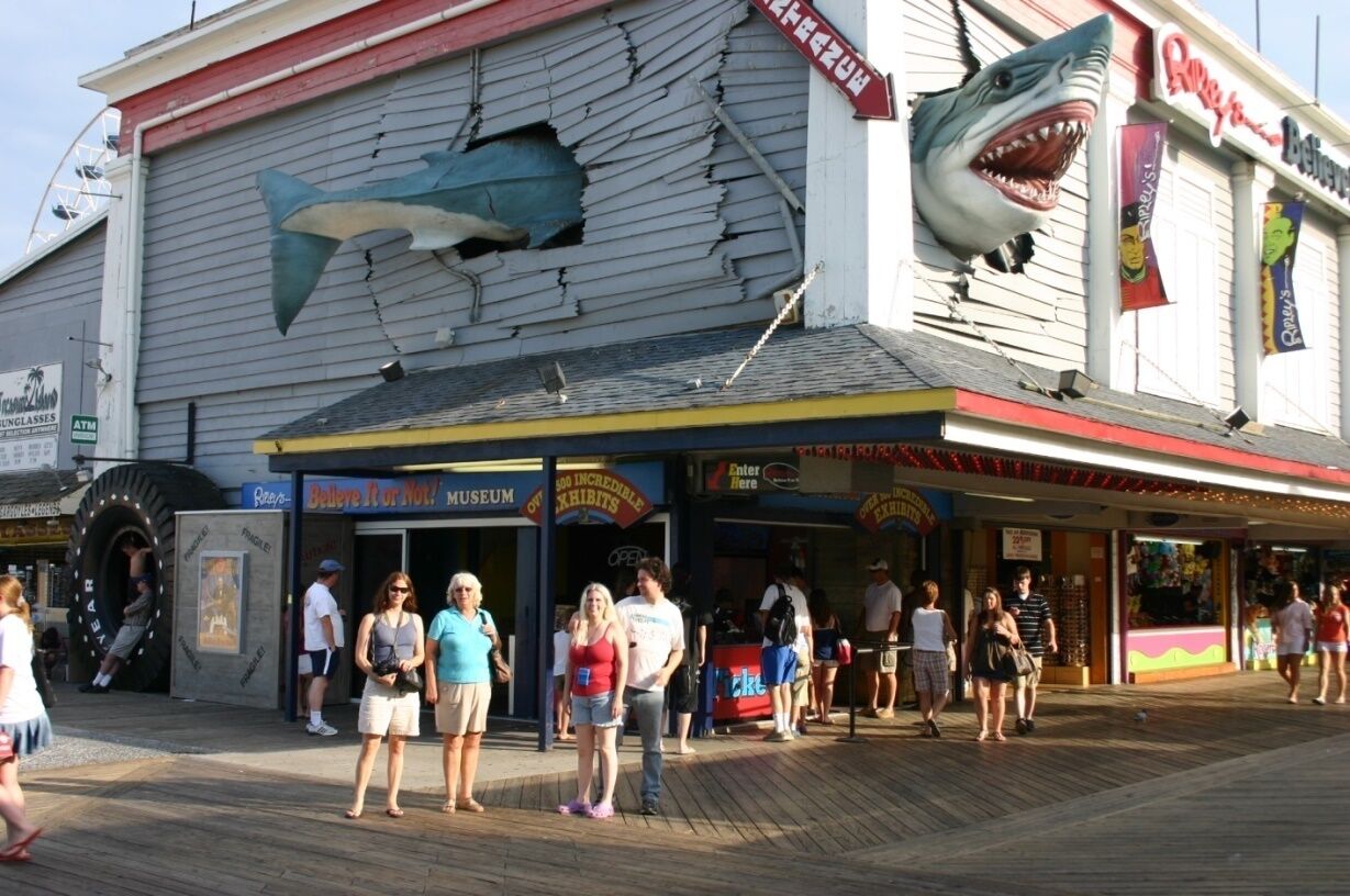 A boardwalk with a large shark mural on a building, a museum, and a restaurant.