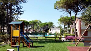 Un parque infantil con un sube y baja, un tobogán y una estructura para escalar.