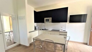 Una cocina moderna con una isla central, microondas y un salpicadero negro.