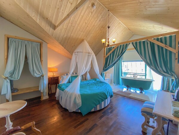 Un dormitorio con cama de dosel, bañera y techo de madera.
