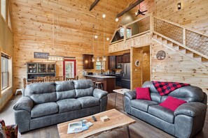 Cozy living area with sofas, kitchenette, and staircase to upper level.
