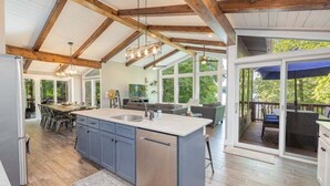 Een ruime keuken met een groot eiland, houten balken en een eethoek met uitzicht.