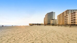 A beach with a pier and high-rise buildings in the background.
