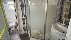 Un baño con cabina de ducha de vidrio, un lavabo y un inodoro.