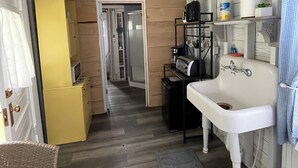 Una cocina compacta con un lavamanos blanco, armarios de madera y un refrigerador amarillo.