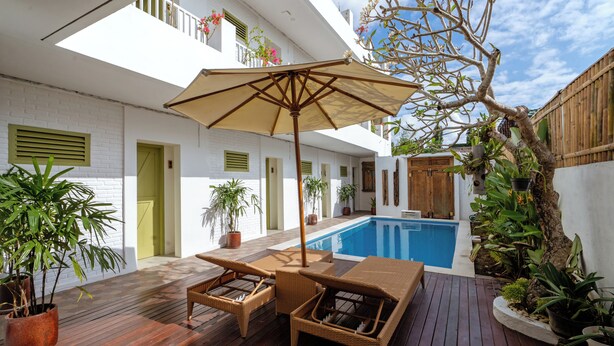 A wooden deck with a pool, wicker furniture, and potted plants. - Honu Studio Living Bali (Pererenan)