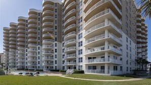 A multi-story residential building with balconies, a swimming pool, and a well-maintained lawn. - 705 St Maarten - Daytona Beach Oceanfront Vacations, Inc (Daytona Beach Shores)