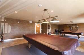 A billiards room with a pool table, two chairs, a small table, and a decorative mirror on the wall. - #705 St. Maarten 3/3 Luxury Oceanfront Condo Daytona Beach Shores (Daytona Beach Shores)