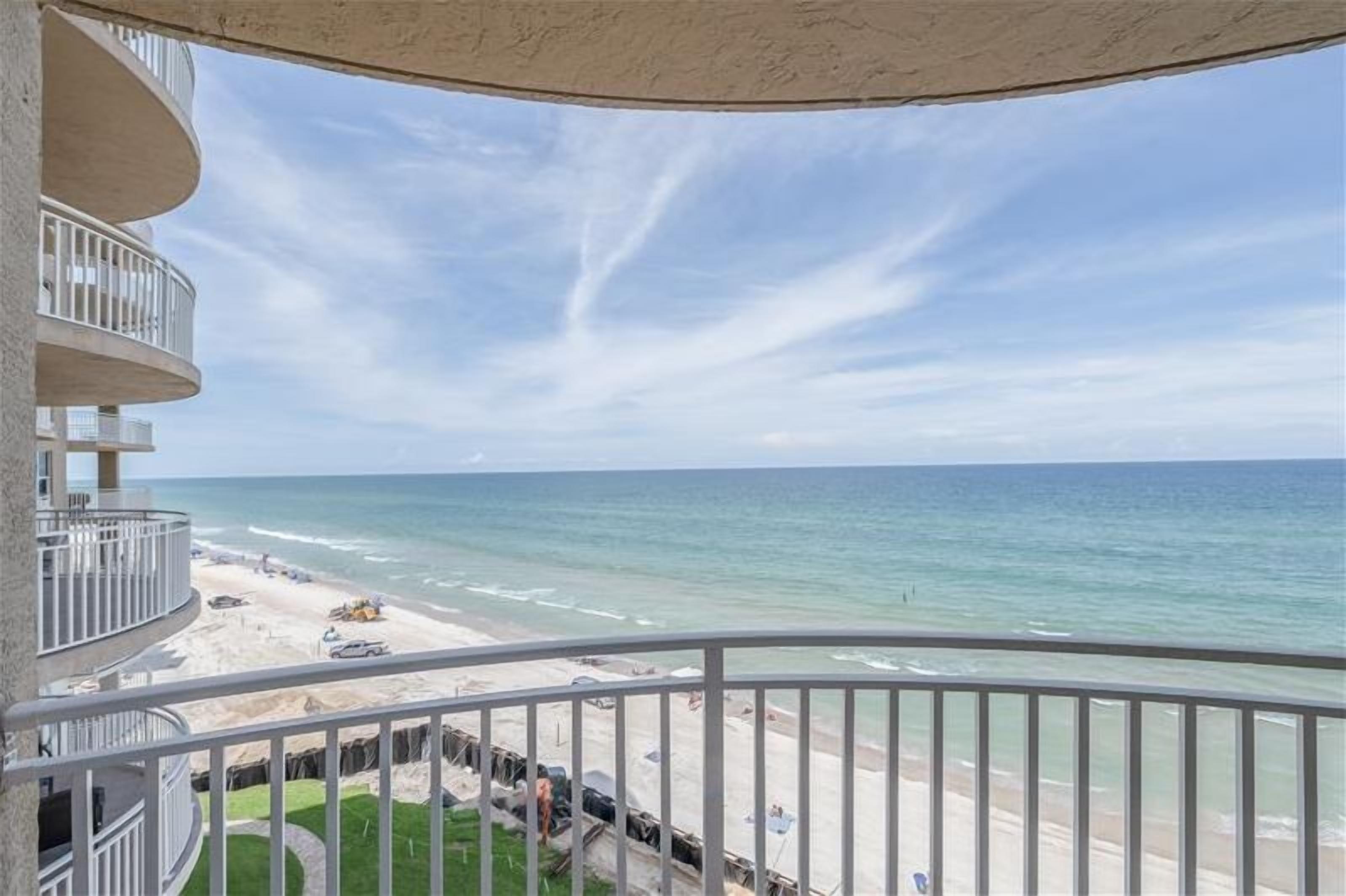 A balcony with a view of the beach and ocean.
