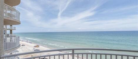 A balcony with a view of the beach and ocean.