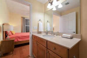 Une salle de bain d’hôtel avec un grand miroir, un lavabo et une commode avec des tiroirs.