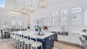 A spacious kitchen with a central island, white cabinetry, stainless steel appliances, and pendant lighting. - Luxe, Pet-Friendly Home@Cinnamon Shore South w/ Amenities & Gulf Glimpses! (Port Aransas)