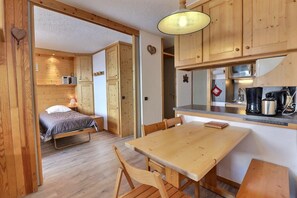A compact room with a bed, a dining table, and a kitchenette.