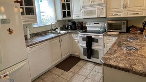 A kitchen with white cabinets, a microwave, a stove, and a sink. - Welcome to Your Ideal Getaway in The Villages! (The Villages)