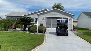A residential house with a garage, a driveway, and a golf cart parked in front. - Welcome to Your Ideal Getaway in The Villages! (The Villages)