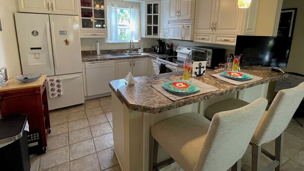 A kitchen with white cabinets, a granite countertop, a built-in oven, a microwave, a sink, and a ceiling fan. - Welcome to Your Ideal Getaway in The Villages! (The Villages)