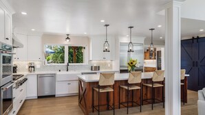 A modern kitchen with white cabinetry, a central island with bar stools, stainless steel appliances, and pendant lighting. - Spectacular Healdsburg Manor-4BR/4.5BA, POOL+2 SPA! (Healdsburg)