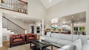 A spacious living area with a large sofa, two leather chairs, a coffee table, and a staircase leading to an upper level. - Spectacular Healdsburg Manor-4BR/4.5BA, POOL+2 SPA! (Healdsburg)