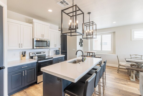 A modern kitchen with white cabinets, stainless steel appliances, and a central island with bar stools.