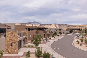 A modern residential area with multi-story buildings, a curved road, and a mountainous backdrop.