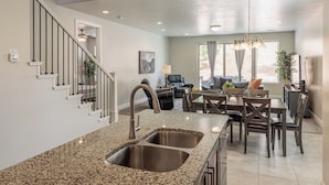A kitchen with granite countertops, stainless steel sinks, and a dining area with dark wood furniture. - Family 4BR Sleeps 23 - Private Hot Tub Near Pool (St. George)