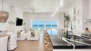 A modern kitchen with a large island, white cabinetry, and a view of the ocean.