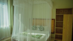 A room with a bed under a white canopy, a wooden wardrobe, and a window with sheer curtains. - Ekhaya Crescent Hotel (Mbarara)