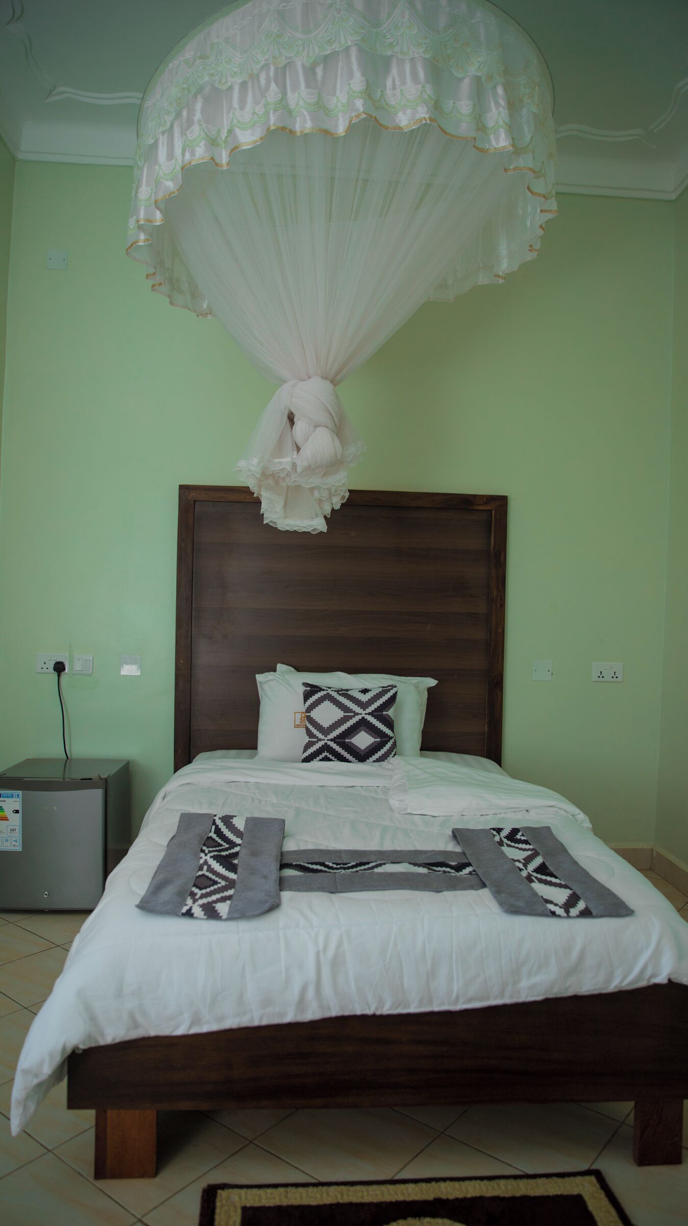 A bed with a canopy, a bedside table, and a patterned pillow.