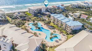 A resort with multiple buildings, a central pool area, and a beach view.