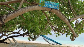 A beach scene with a sign reading "1AHTBADHOO South Ari, Maldives" and a hammock under a tree.