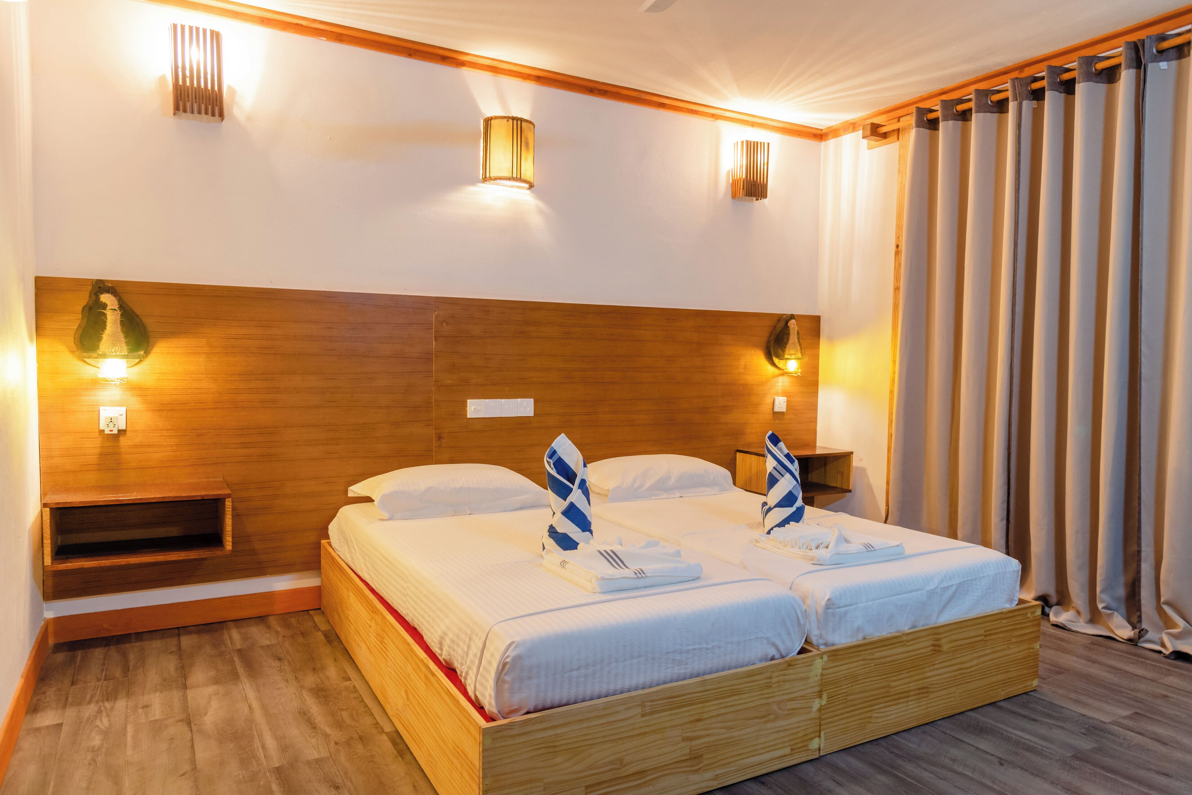 A double bed with a wooden headboard, two bedside tables, and wall-mounted lights.