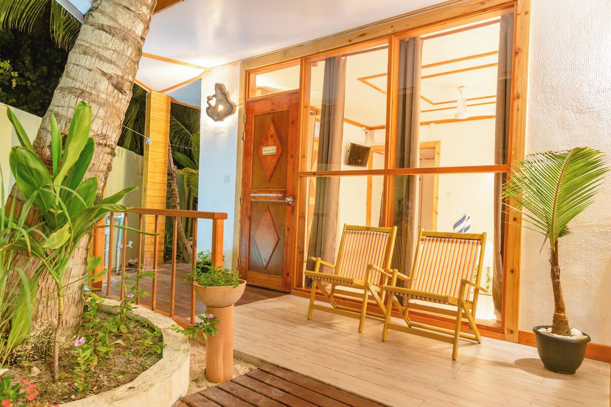 A wooden deck with two chairs and a potted plant.