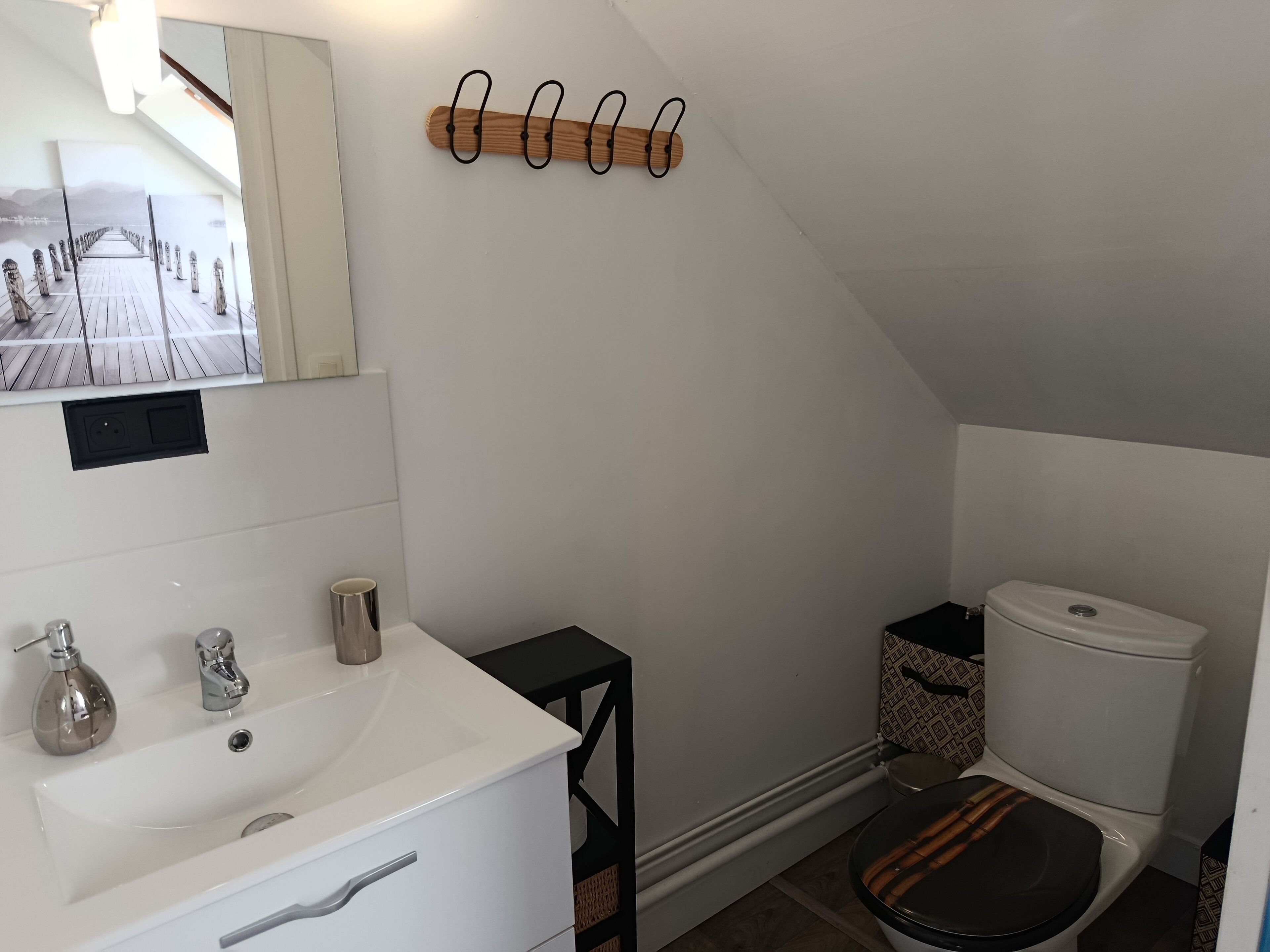 A bathroom with a white sink, mirror, and a wooden coat rack.