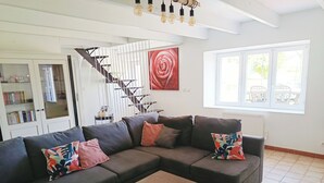 Un salon moderne avec un canapé d’angle, une table basse en bois et un escalier.
