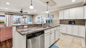 A modern kitchen with white cabinets, granite countertops, and stainless steel appliances. - Surfing Gecko: Oceanfront, Shared Pool, Dogs OK (Kill Devil Hills)