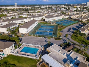 A residential area with multiple apartment buildings, a large swimming pool, and several tennis courts.