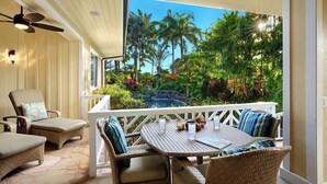 A covered outdoor seating area with wicker furniture, a table with drinks, and a view of a tropical garden and waterfall. - Pinnacle at Poipu -  6 Bedroom Luxury Estate - Amazing Views & Salt Water Pool! (Koloa)
