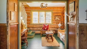 A log cabin interior with a staircase, wooden walls, a dining area, and a bed. - Big Sky Vacation Rentals: Chief Joseph Log Home (Big Sky)