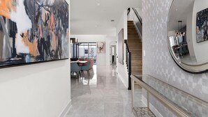 A modern interior with a staircase, a dining area, and a hallway leading to a bedroom. - The Marvelous | Brand NEW home w toy theme RM, pool, grand LR/DR, near Universal (Orlando)